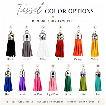 A color options chart for Tassel jewelry, showing thirteen numbered tassel charms in different colors including Black, Gray, White, Red, Orange, Yellow, Blue, Purple, Hot Pink, Light Pink, Green, Olive, and Teal. Each tassel has a silver-toned metal cap and is labeled with its color name underneath on a white background.