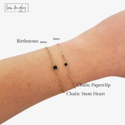 Gold bracelet on a wrist with labeled chain type and birthstone size, lora Douglas Jewelry brand visible.