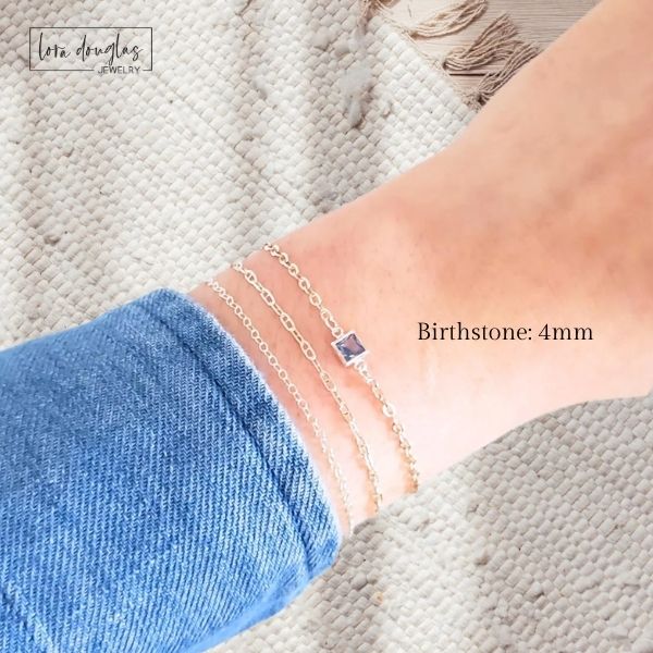 Close-up of a person's wrist wearing a bracelet with a blue stone, on a textured surface.