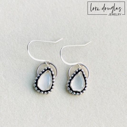 A pair of sterling silver dangle earrings with a teardrop-shaped moonstone stone in the center