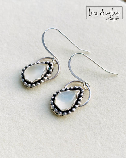 A pair of sterling silver dangle earrings with a teardrop-shaped moonstone stone in the center