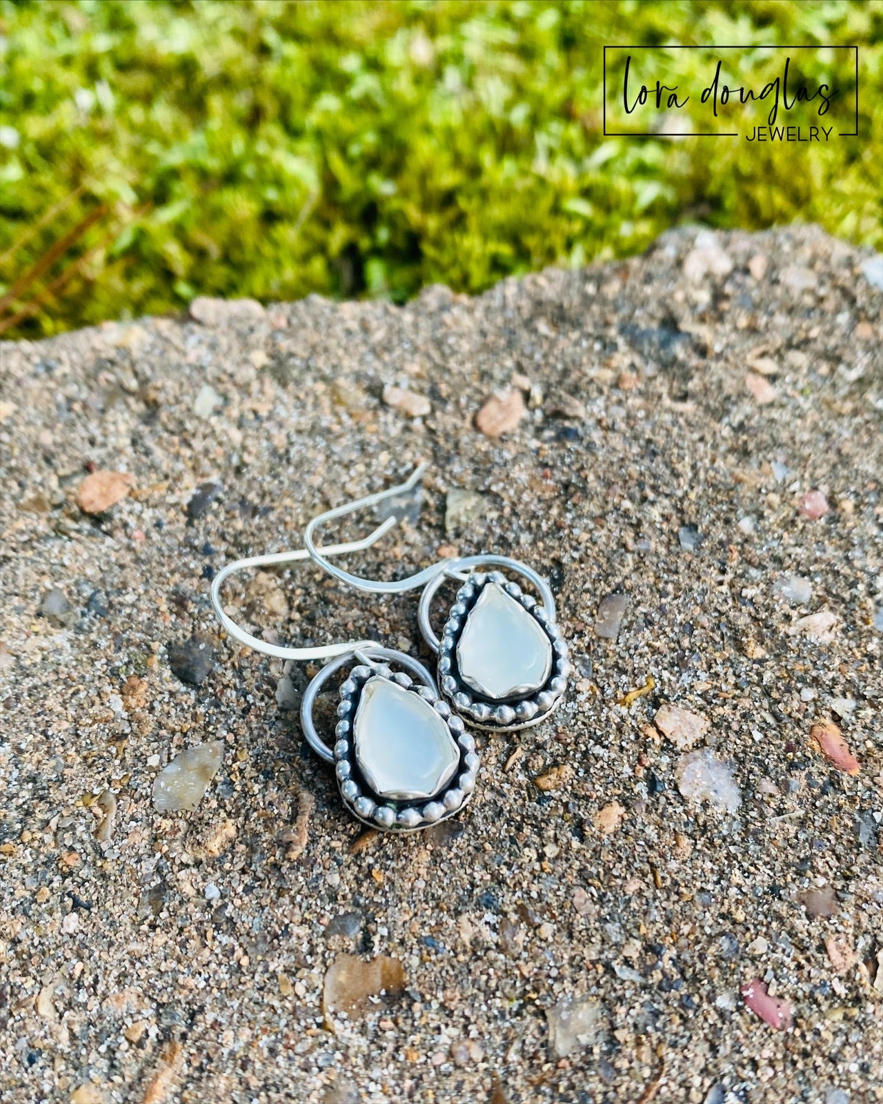 A pair of sterling silver dangle earrings with a teardrop-shaped moonstone stone in the center