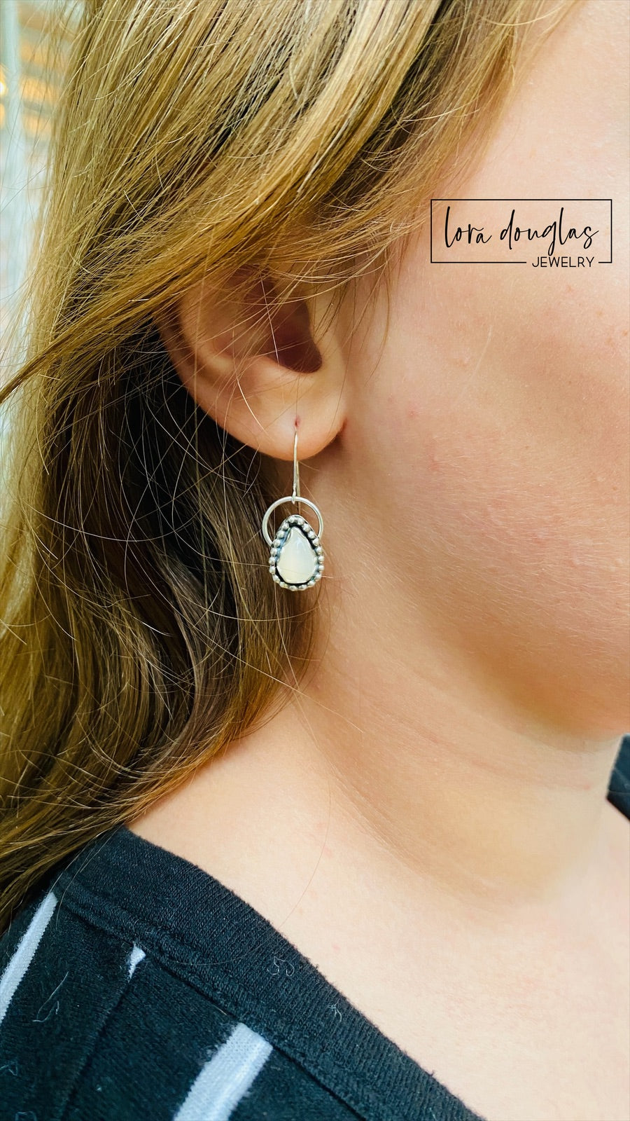 A pair of sterling silver dangle earrings with a teardrop-shaped moonstone stone in the center