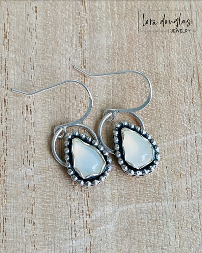 A pair of sterling silver dangle earrings with a teardrop-shaped moonstone stone in the center