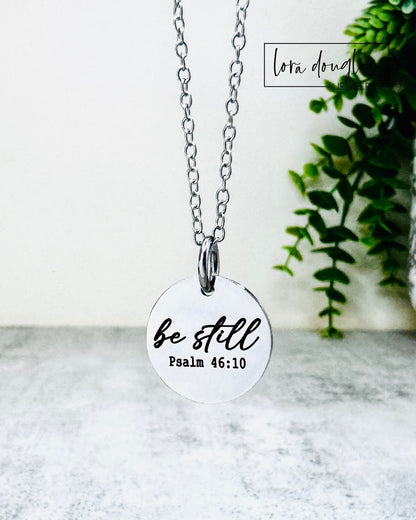 Necklace with a pendant that reads 'be still Psalm 46:10' on a white background.