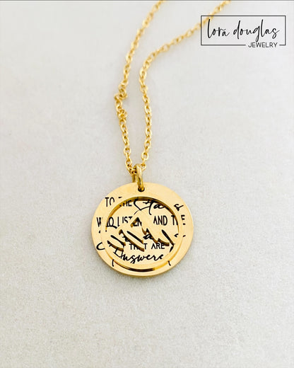 A gold stainless steel necklace with a round pendant engraved with the quote 'To the Stars who listen - and the Dreams that are Answered' and a laser cut mountain pendant.