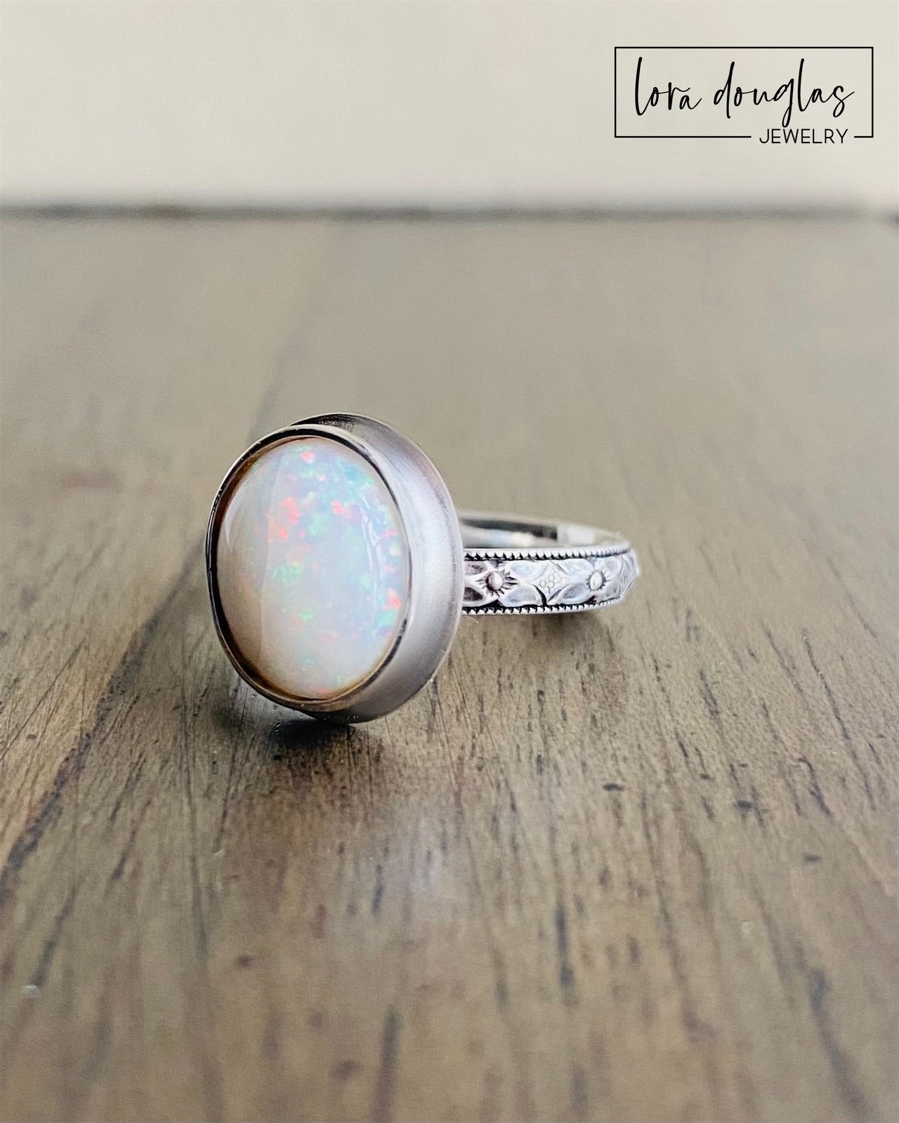 A sterling silver ring with a hand-cut opal cabochon centerpiece, set in an oval setting.
