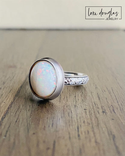 A sterling silver ring with a hand-cut opal cabochon centerpiece, set in an oval setting.