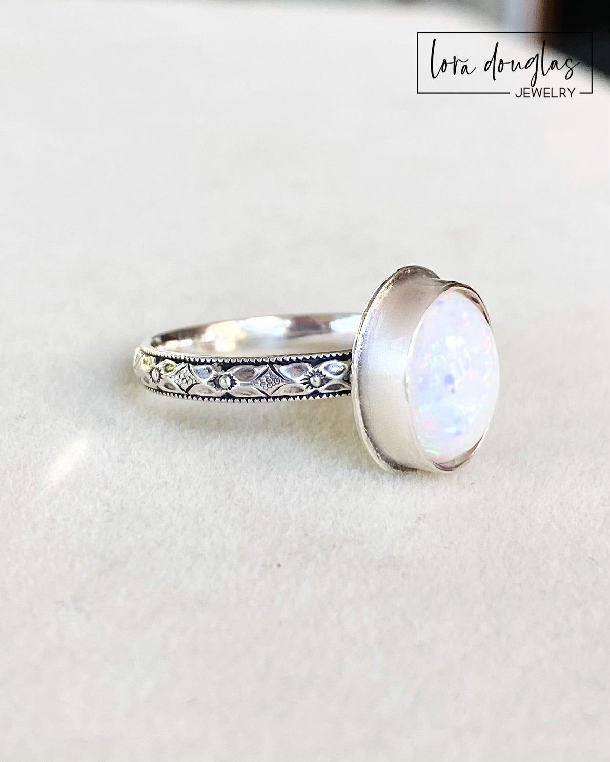 A sterling silver ring with a hand-cut opal cabochon centerpiece, set in an oval setting.