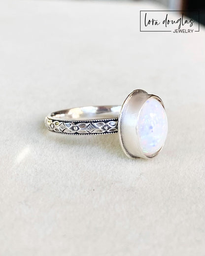 A sterling silver ring with a hand-cut opal cabochon centerpiece, set in an oval setting.