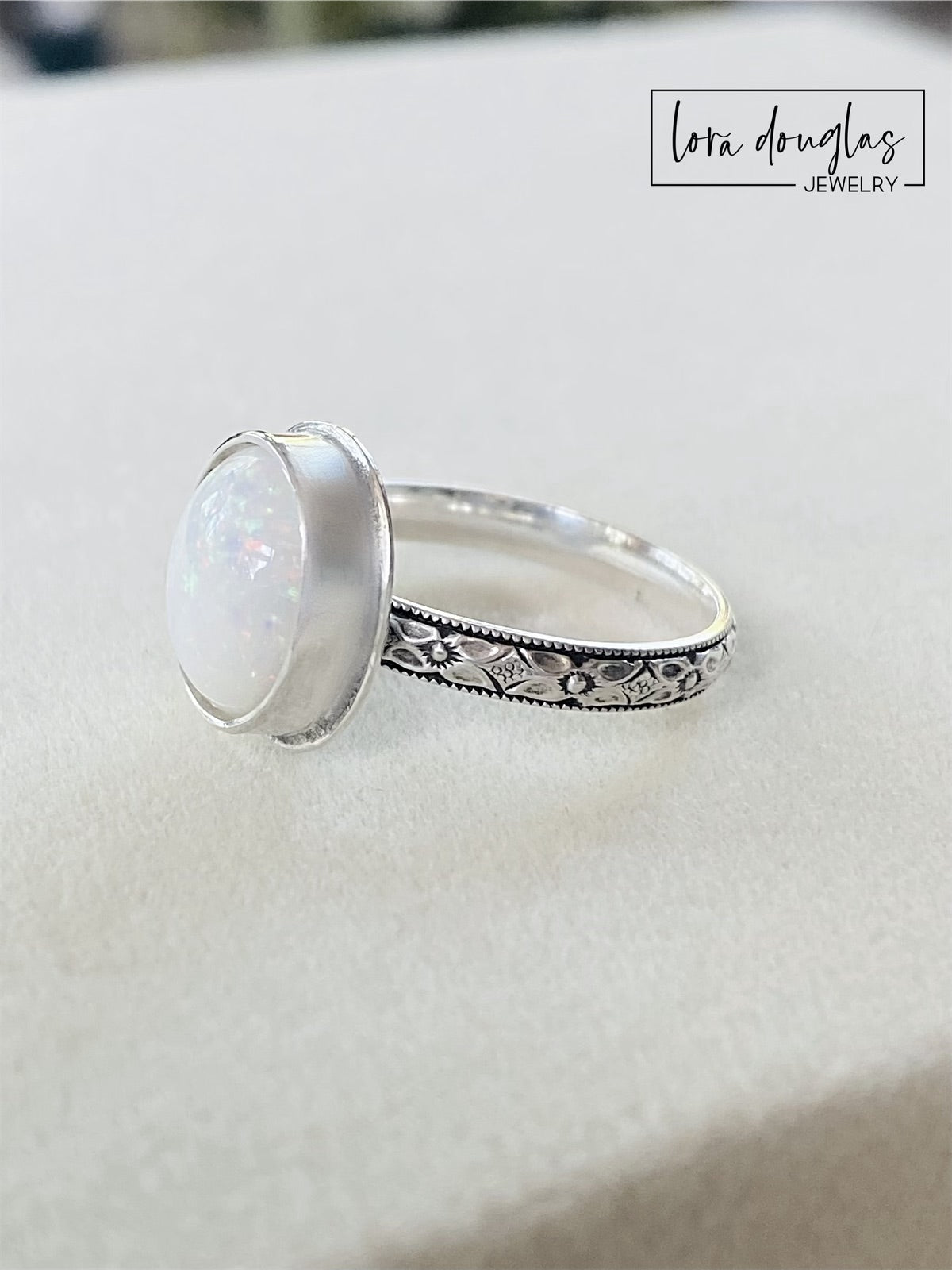 A sterling silver ring with a hand-cut opal cabochon centerpiece, set in an oval setting.