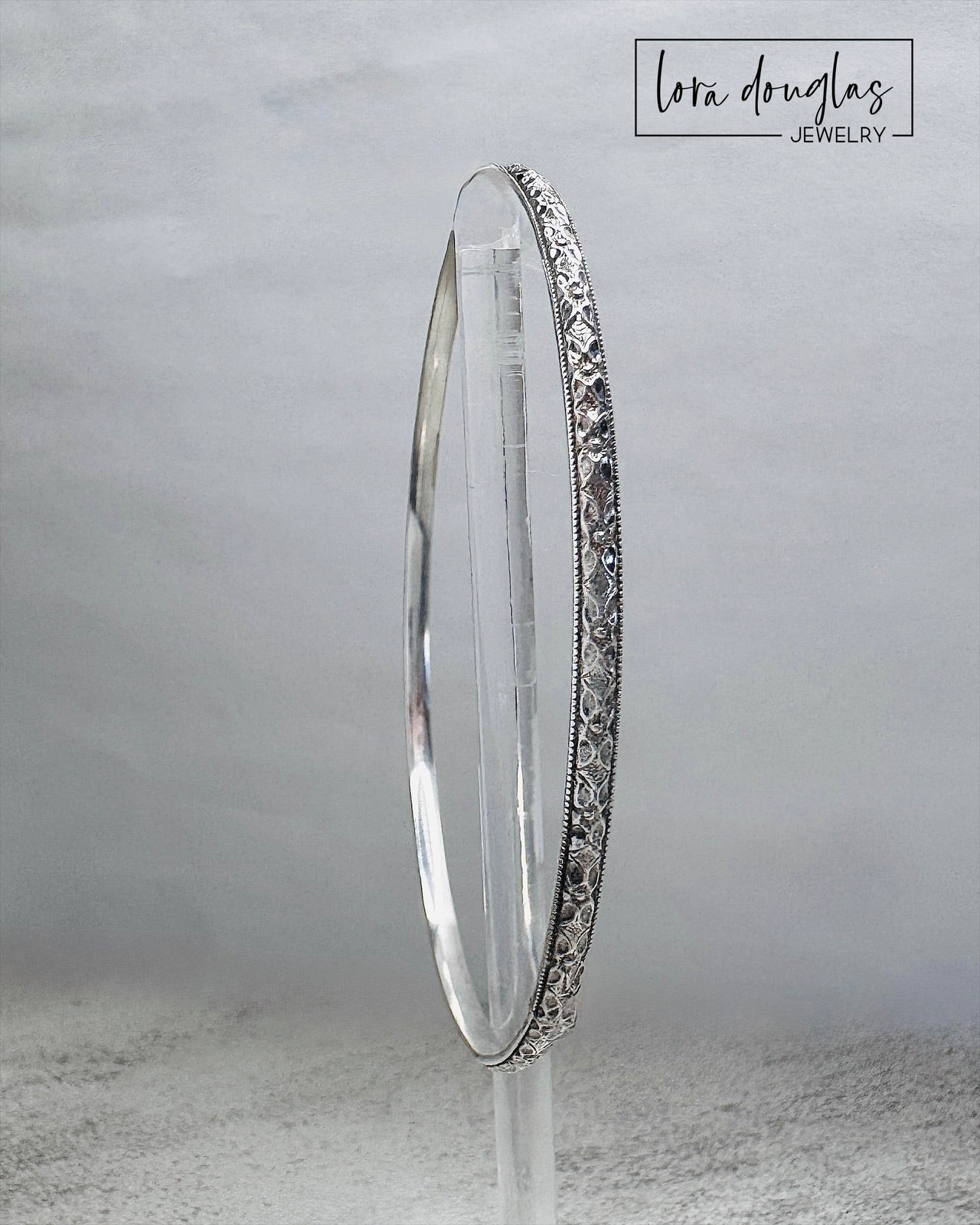 Artisan sterling silver bangle bracelet featuring detailed texture and high polish handmade design.