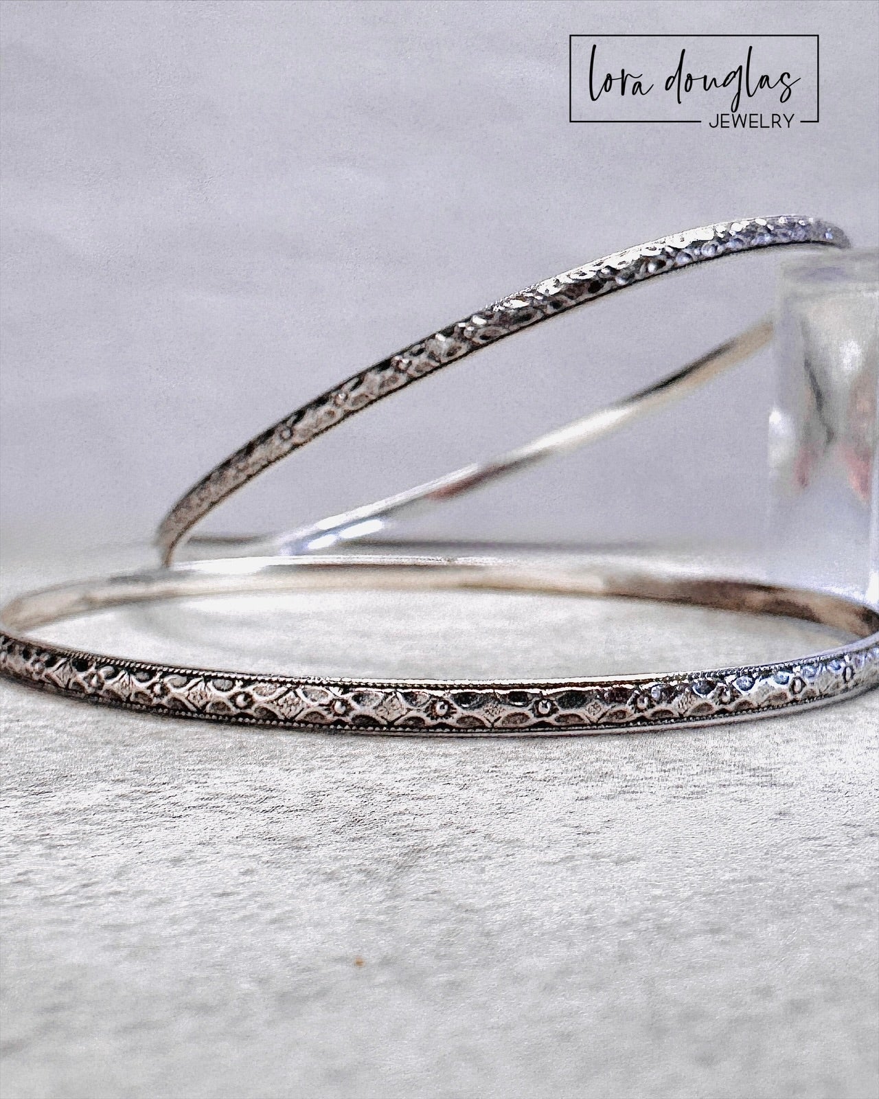Stackable sterling silver bangle bracelet with decorative texture and smooth polished interior.
