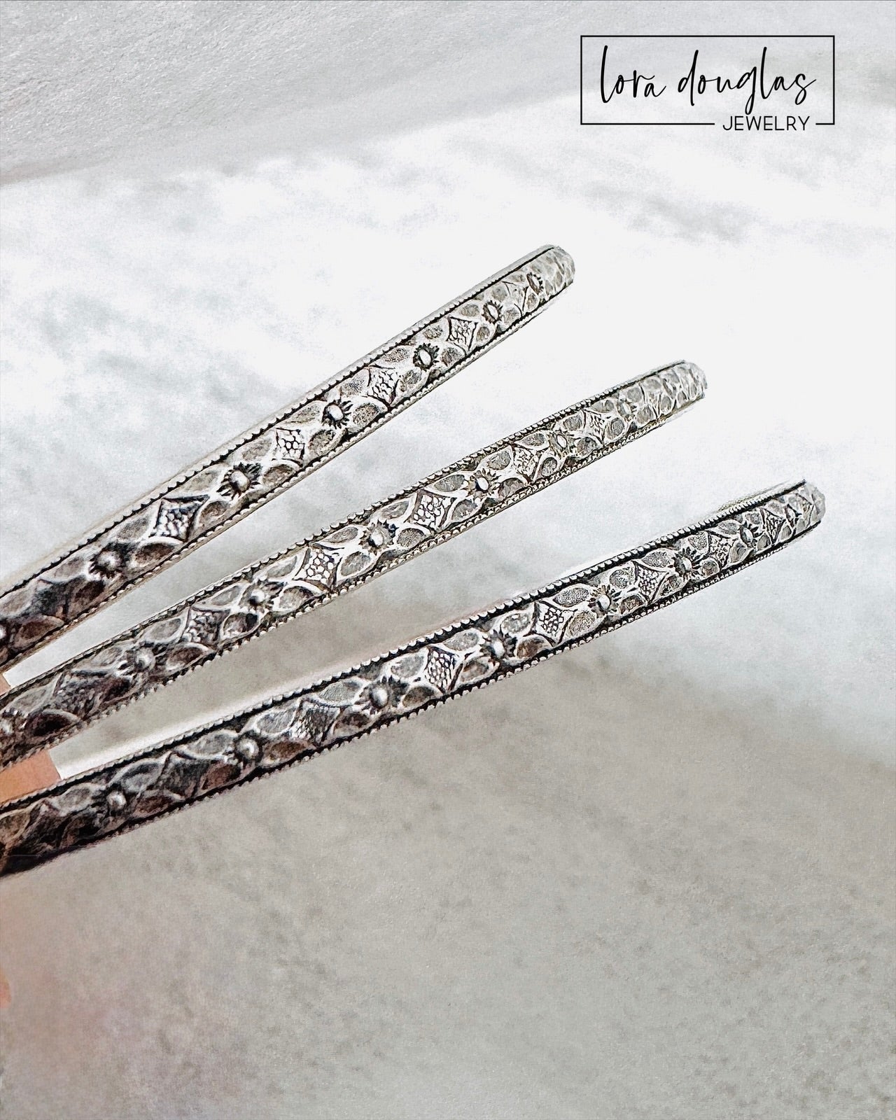 Handmade sterling silver bangle bracelet shown on display stand highlighting textured finish.