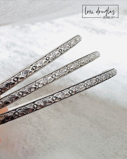 Handmade sterling silver bangle bracelet shown on display stand highlighting textured finish.