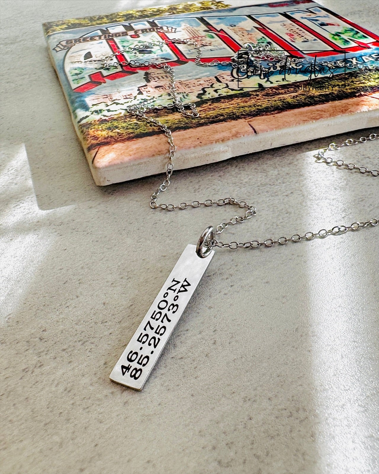 A custom necklace engraved with GPS coordinates or latitude and longitude of a special place on a silver stainless steel pendant and chain