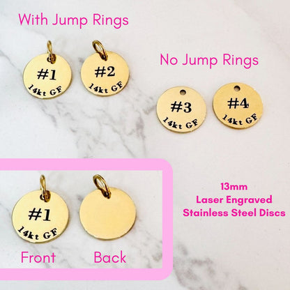 Four round, gold-colored stainless steel discs by Lora Douglas Jewelry are shown—two with jump rings and two without. These 13mm Permanent Jewelry ID Tags for Displays are laser engraved for durability (chains not included).