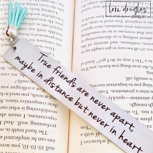 long distance friendship bookmark engraved with True Friends Are Never Apart quote on stainless steel metal bookmark with leather tassel, personalized friendship gift displayed inside open book with brushed silver finish
