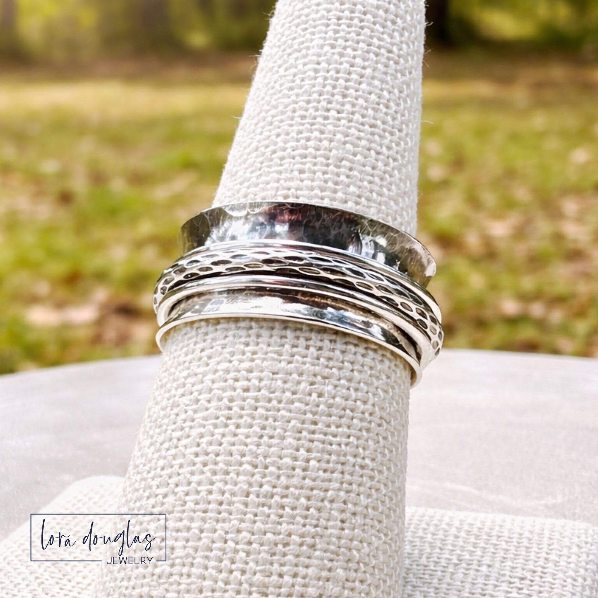 Silver ring on a textured white surface with a blurred natural background