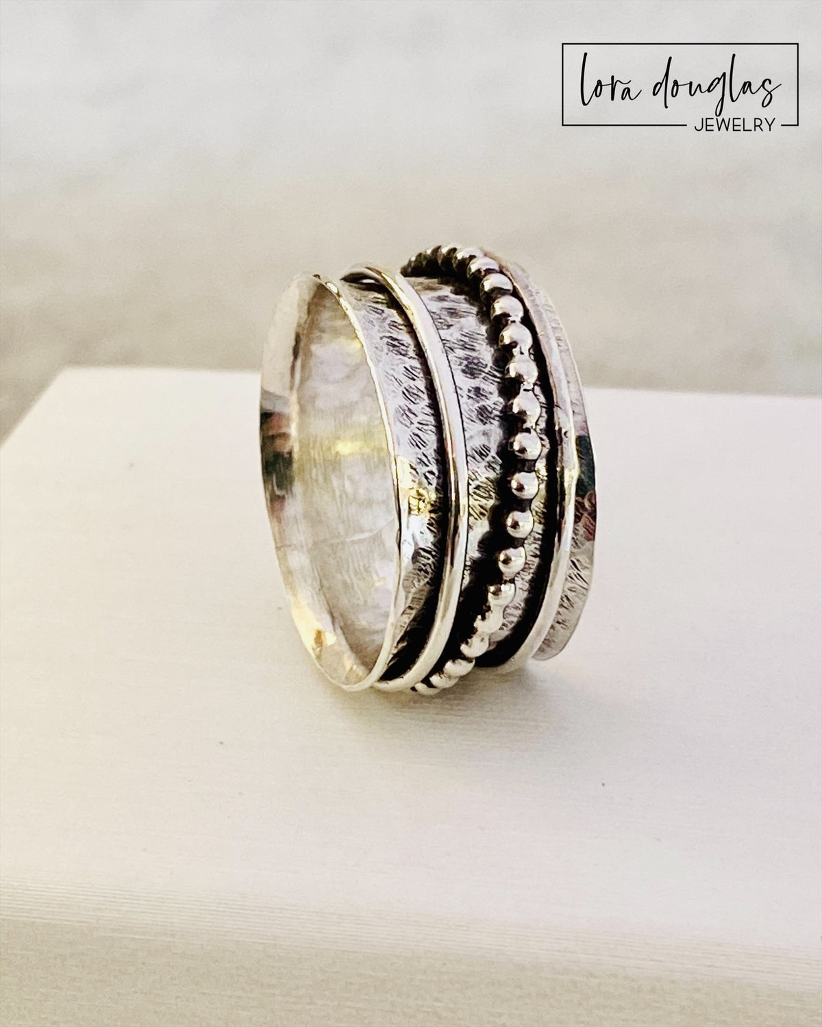 925 sterling silver fidget ring with three moving components that can be spun and moved around the central band, shown as a finished size 8.5 spinner ring for people who enjoy tactile and interactive jewelry.

