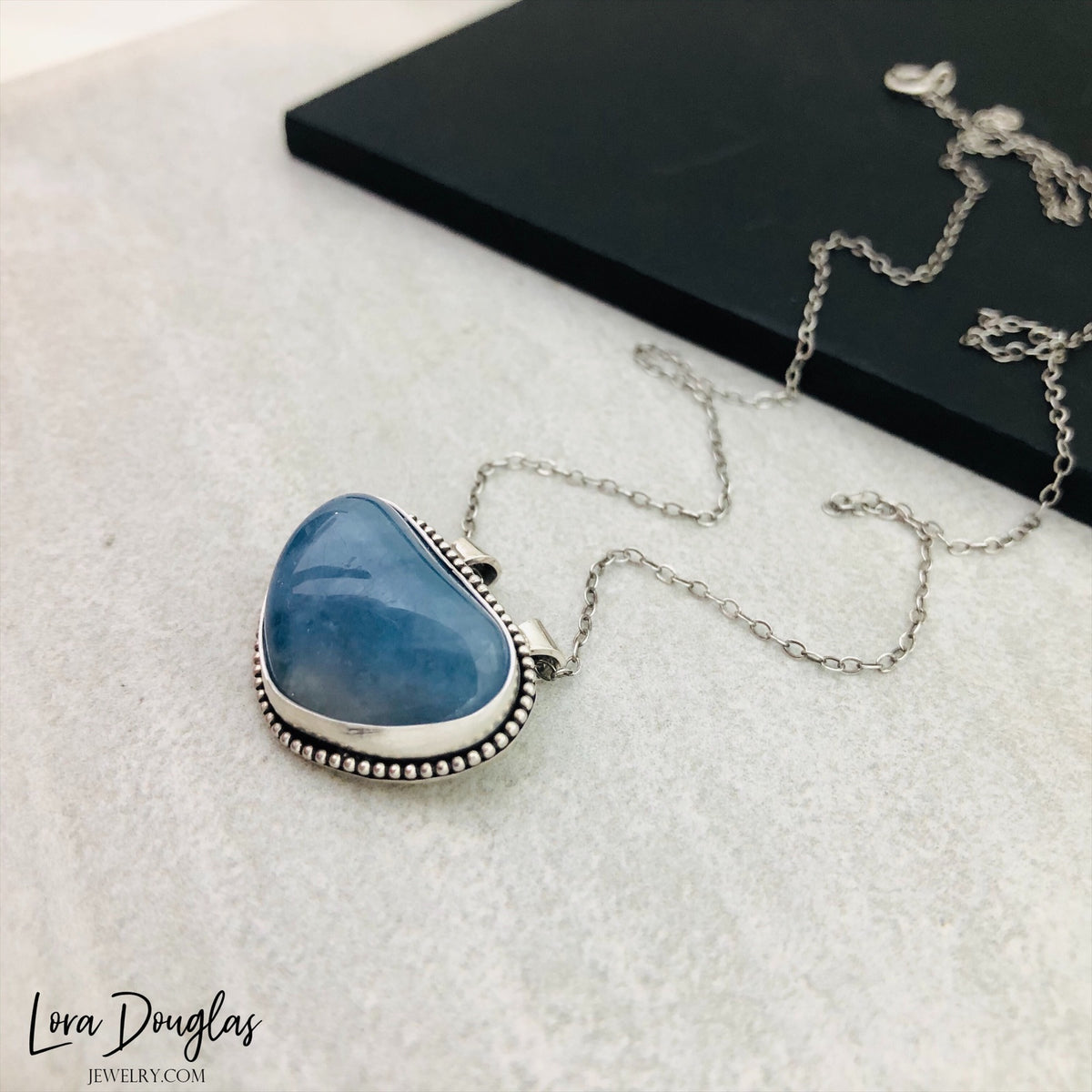 Aquamarine and sterling silver necklace featuring a natural blue gemstone pendant on an 18 inch chain, combining the soft color of aquamarine with an antique patina silver finish for added contrast.
