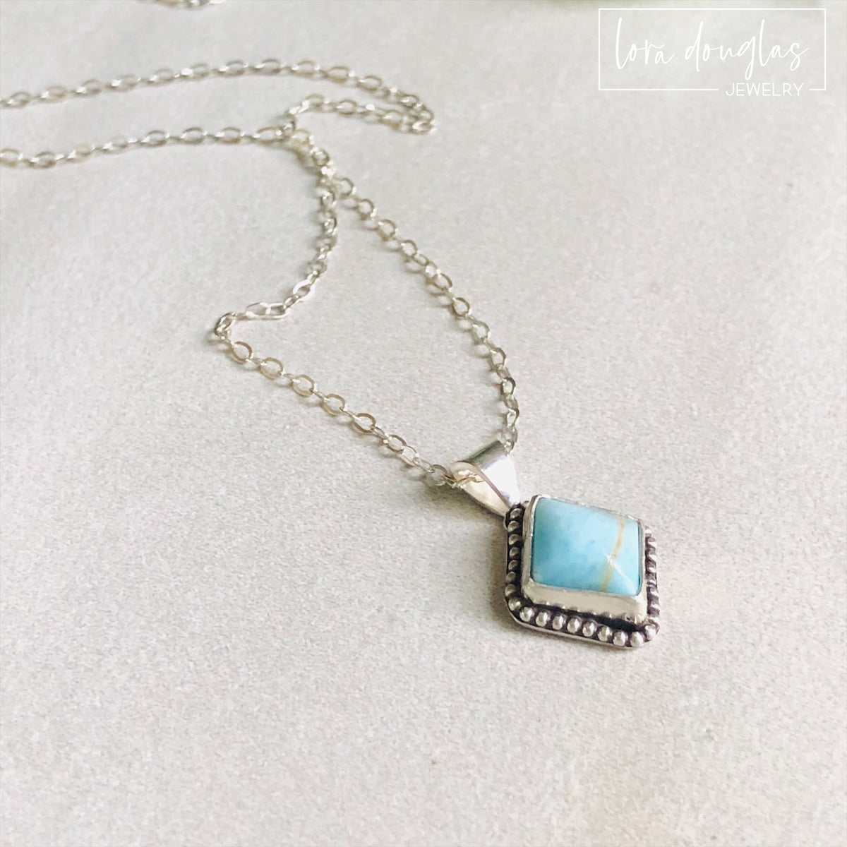 Blue turquoise pendant necklace featuring a natural 10mm x 9mm gemstone set in sterling silver, with an approximately .7 inch x .4 inch total pendant size and an 18 inch sterling silver chain.
