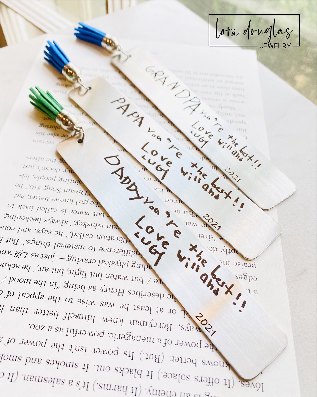 Close up of a personalized handwriting bookmark featuring actual engraved handwriting on brushed stainless steel with a colorful tassel. Custom engraved memorial bookmark created from your uploaded handwritten note or drawing.