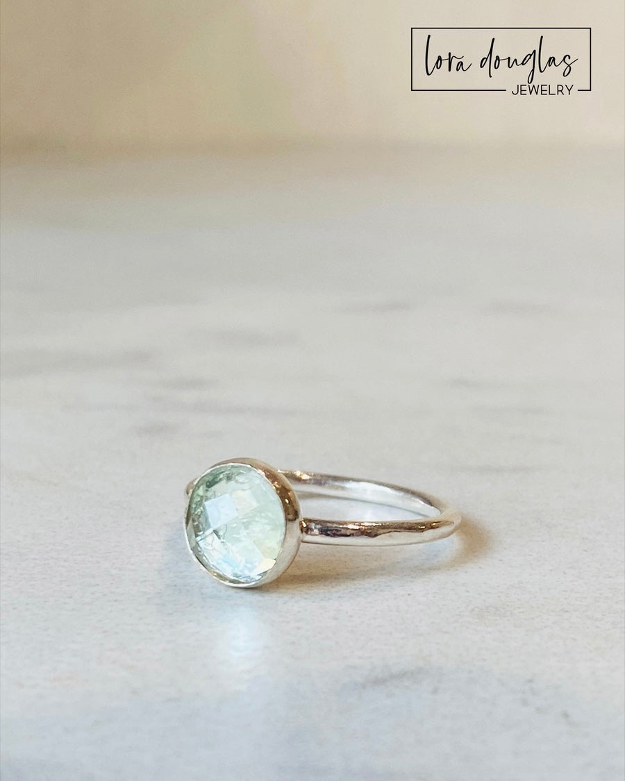 Close view of a green quartz solitaire ring showing the faceted rose cut surface of the 8mm gemstone, also known as green amethyst or prasiolite, set in sterling silver and finished in US size 6.
