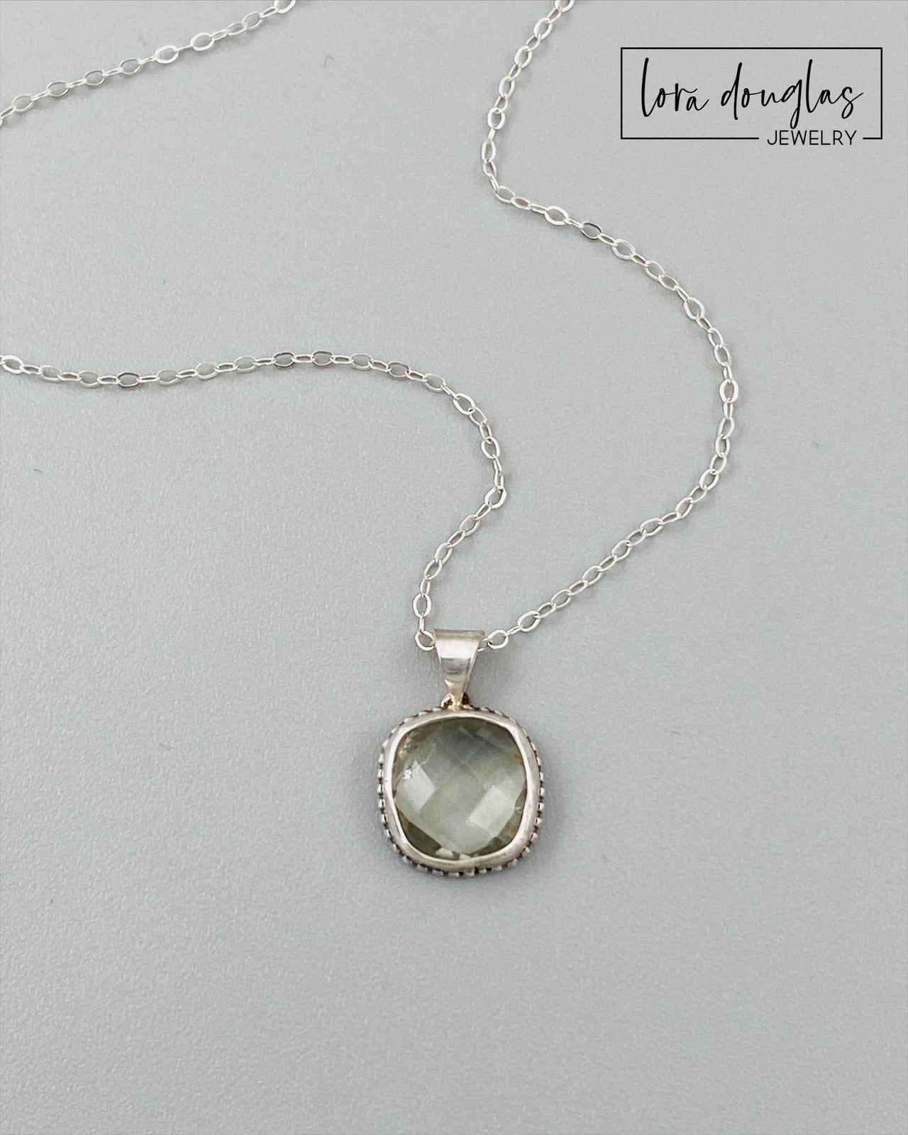 Close view of a hand cut green amethyst gemstone showing the faceted surface and soft green color of the 11mm prasiolite stone, set in sterling silver as a distinctive natural gemstone pendant necklace.
