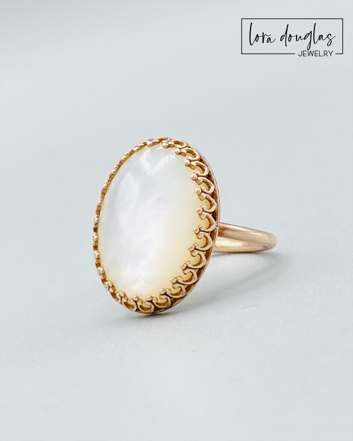 Close view of a natural Mother of Pearl stone set in a bronze ring. The 18 x 13 mm iridescent shell creates a luminous focal point in this size 6 statement ring for women who love unique artisan jewelry.