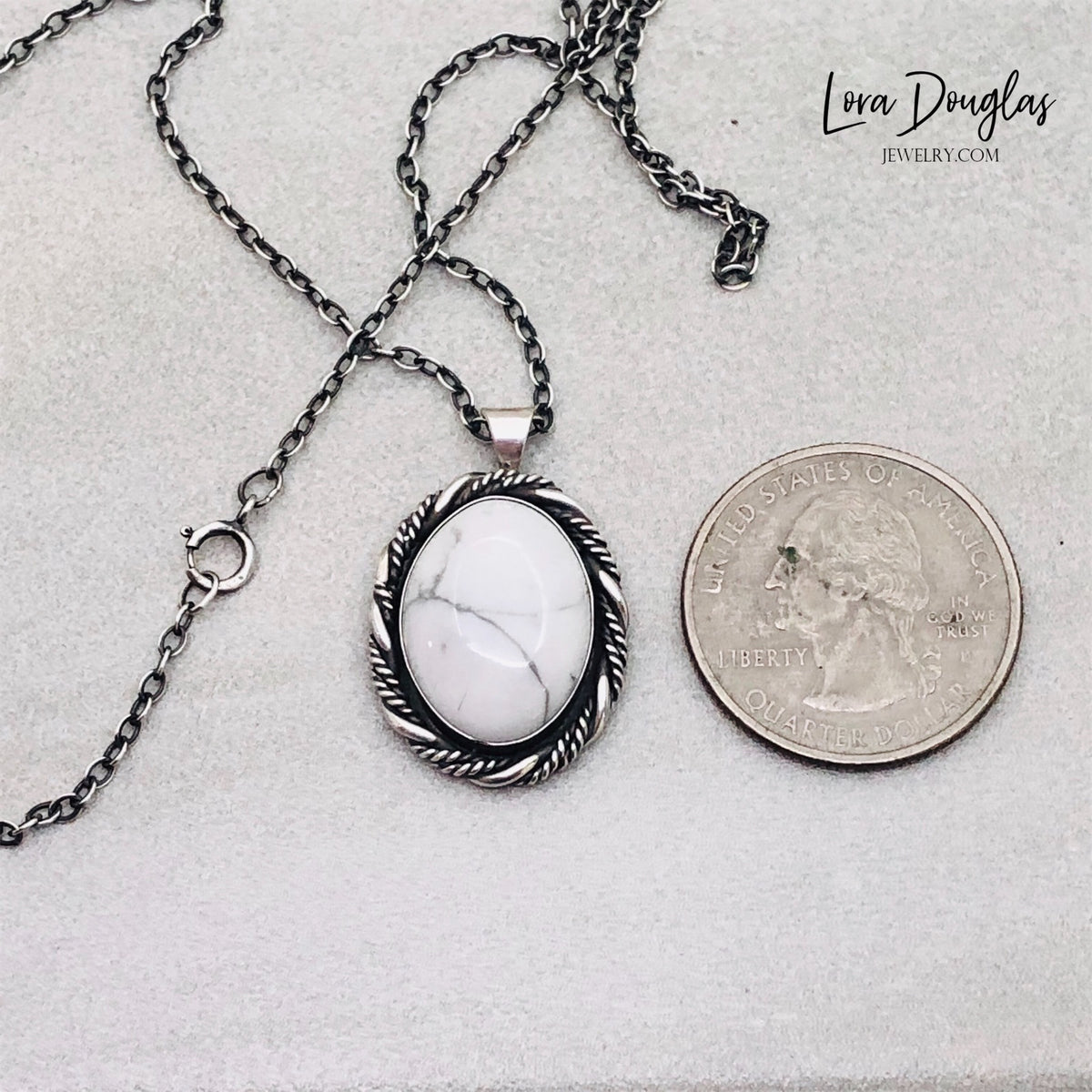Close view of a natural howlite pendant showing the white gemstone and organic gray veining surrounded by handcrafted sterling silver. One of a kind gemstone necklace paired with an 18 inch sterling chain.