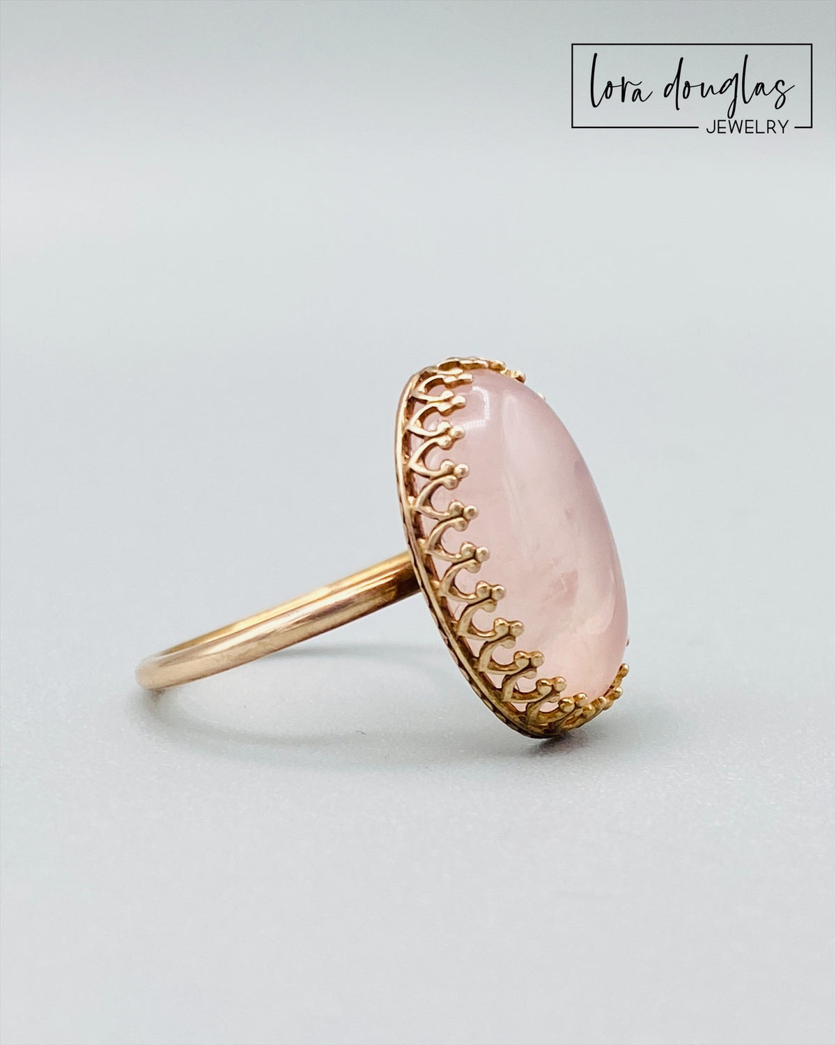 Close view of a natural rose quartz ring showing the soft pink color and character of the 18mm x 13mm gemstone in a warm bronze setting, a finished US size 7.5 ring and meaningful gift for her.
