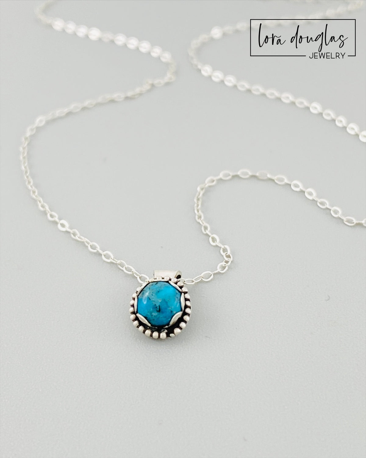 Close view of a natural turquoise pendant showing the 5mm blue gemstone in its sterling silver setting, paired with an antique patina silver chain for a petite December birthstone necklace and gemstone gift.
