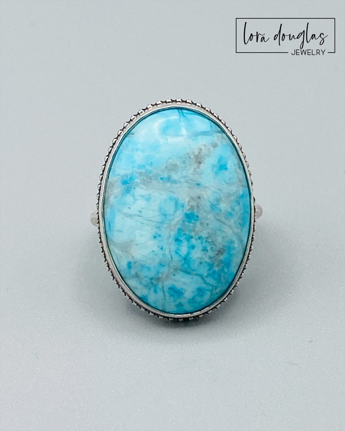 Close view of a natural turquoise ring showing the blue color and individual character of the 26mm x 19mm gemstone in a sterling silver setting, a finished US size 7 statement ring for gemstone jewelry lovers.
