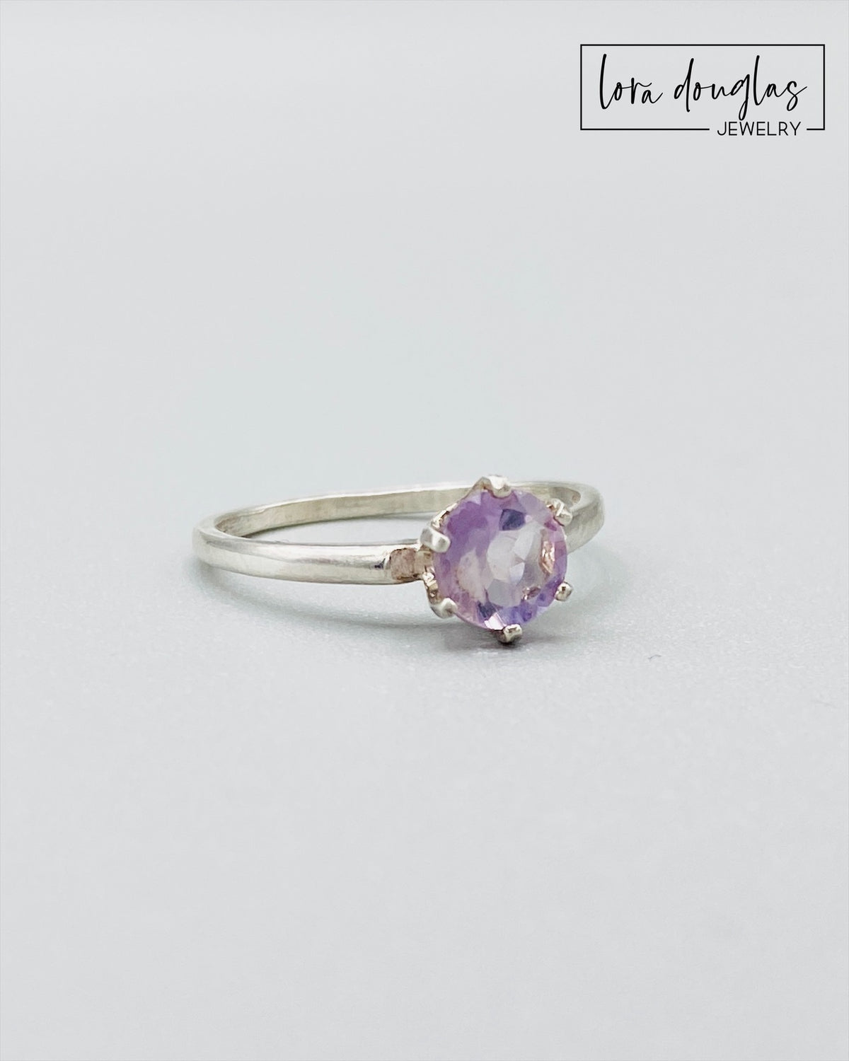 Close view of a pink amethyst ring showing the soft lavender pink color of the 6mm gemstone in a sterling silver solitaire setting, finished in US size 6.5 for shoppers seeking delicate natural stone jewelry.
