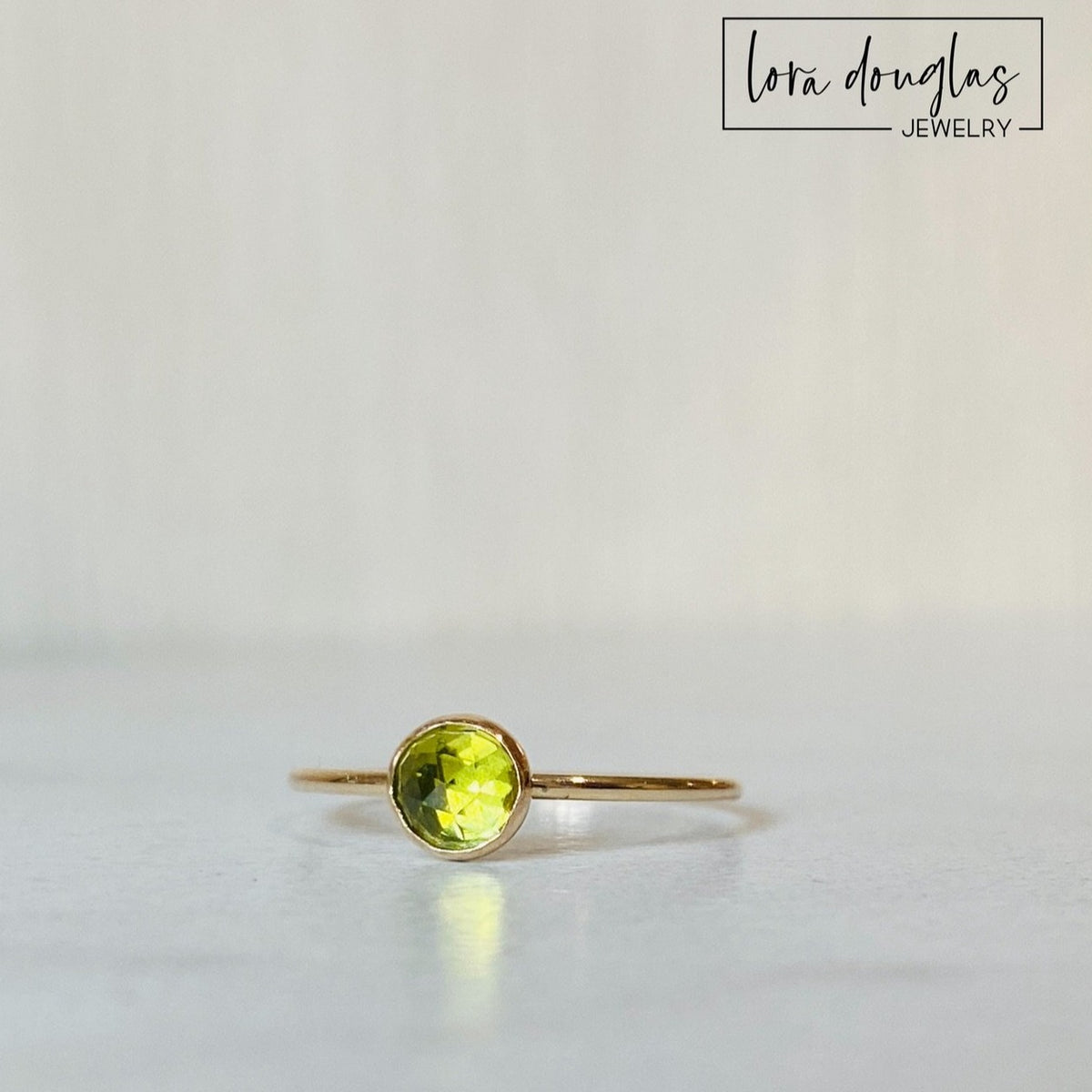 Close view of a rose cut peridot gemstone ring with a faceted 5mm green stone set in warm 14/20 gold filled, a simple solitaire design available as a finished ring in US size 6.

