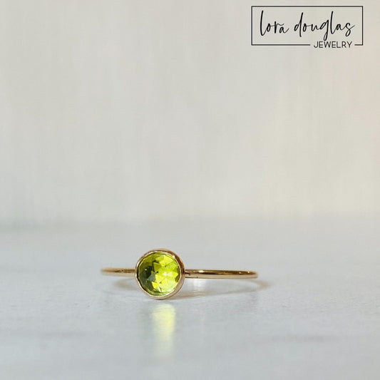 Close view of a rose cut peridot gemstone ring with a faceted 5mm green stone set in warm 14/20 gold filled, a simple solitaire design available as a finished ring in US size 6.
