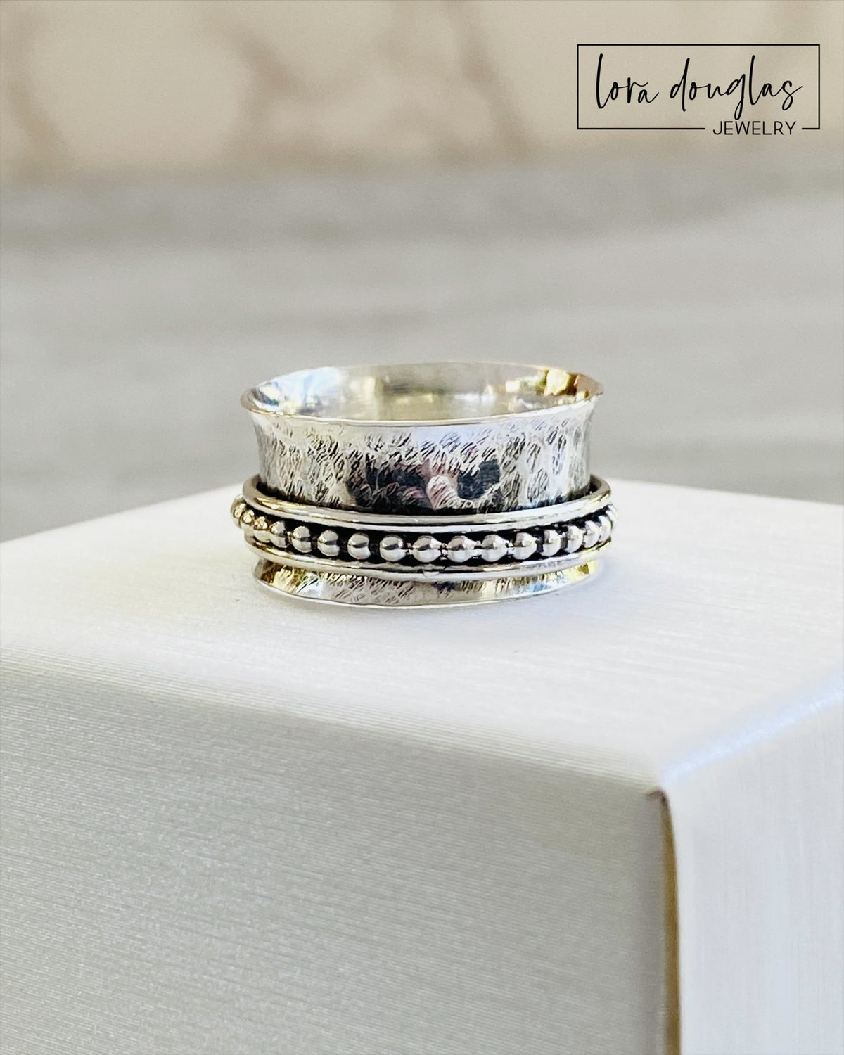 Close view of a sterling silver spinner ring showing three movable components around the central band, with an approximately 0.4 inch wide profile and finished US size 8.5 design for fidget jewelry lovers.
