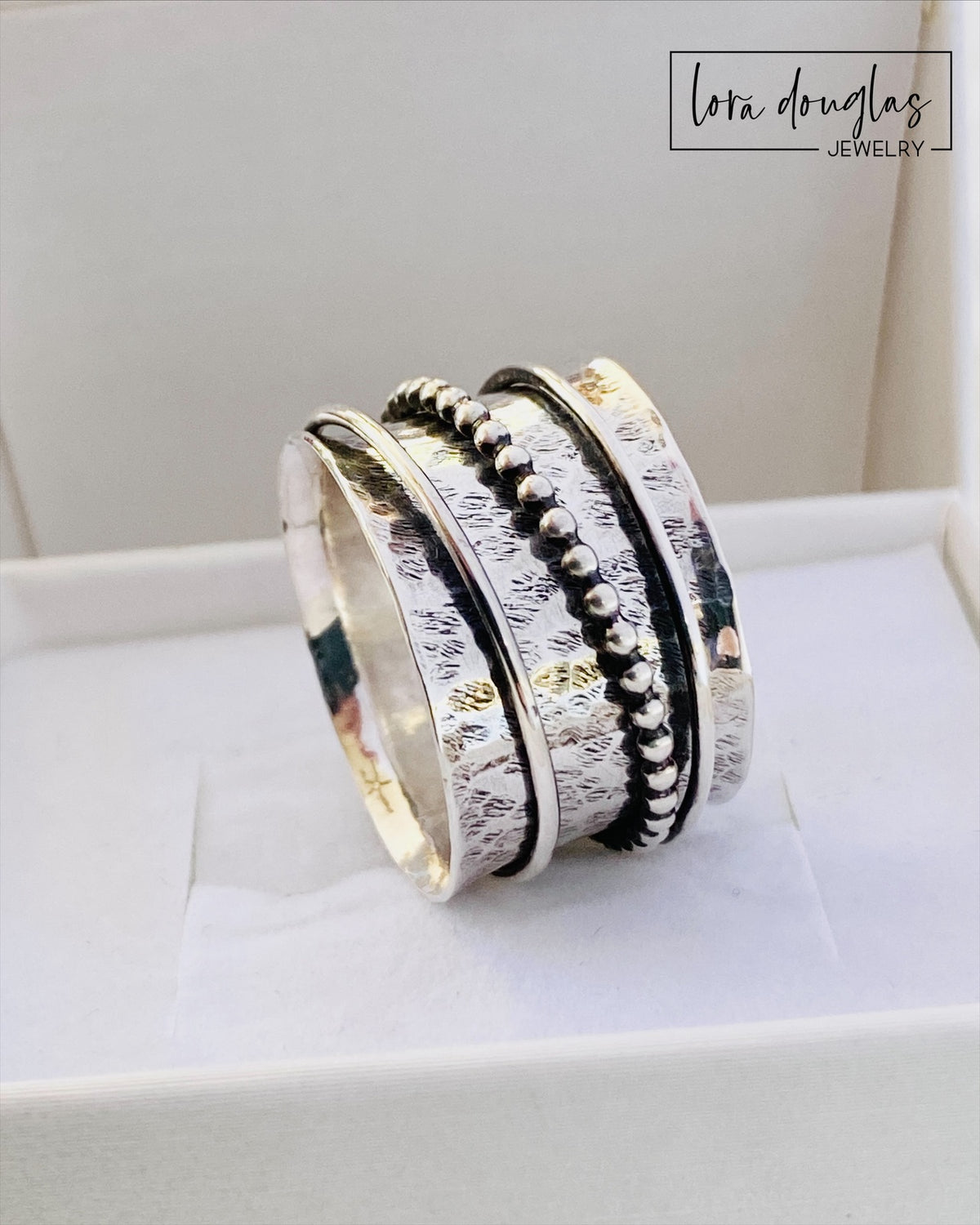 Close view of a sterling silver spinner ring showing three movable components around the central band, with an approximately 1/2 inch wide profile and finished US size 10.5 design for fidget jewelry lovers.
