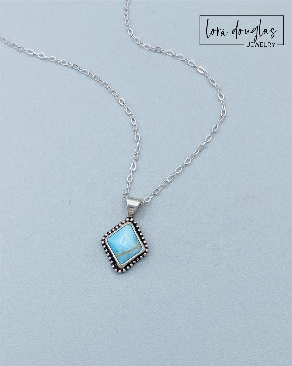 Close view of a turquoise sterling silver pendant highlighting the natural blue gemstone and simple silver setting, a petite necklace that lets the distinctive color and character of the turquoise remain the focal point.
