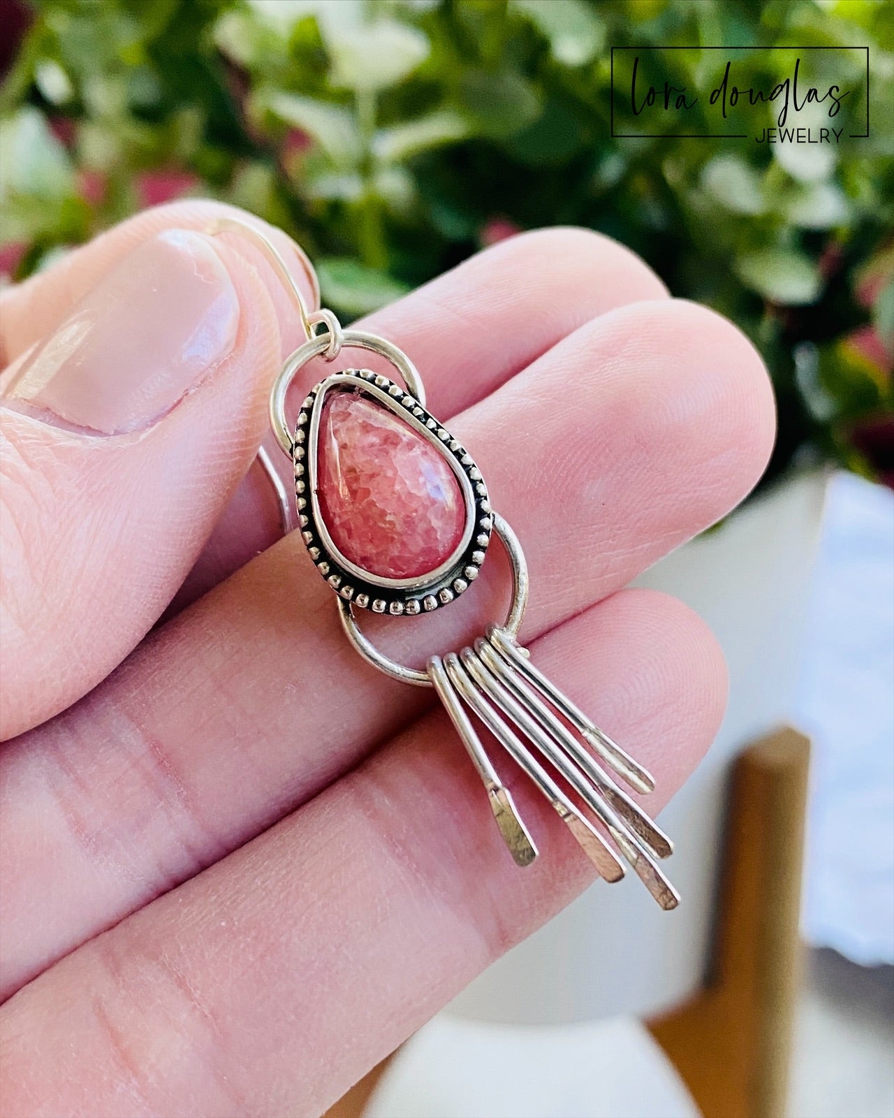 Close view of handcrafted rhodochrosite earrings showing the natural pink teardrop gemstones, sterling silver settings and dangling fringe details that give these approximately 2 inch earrings movement and texture.
