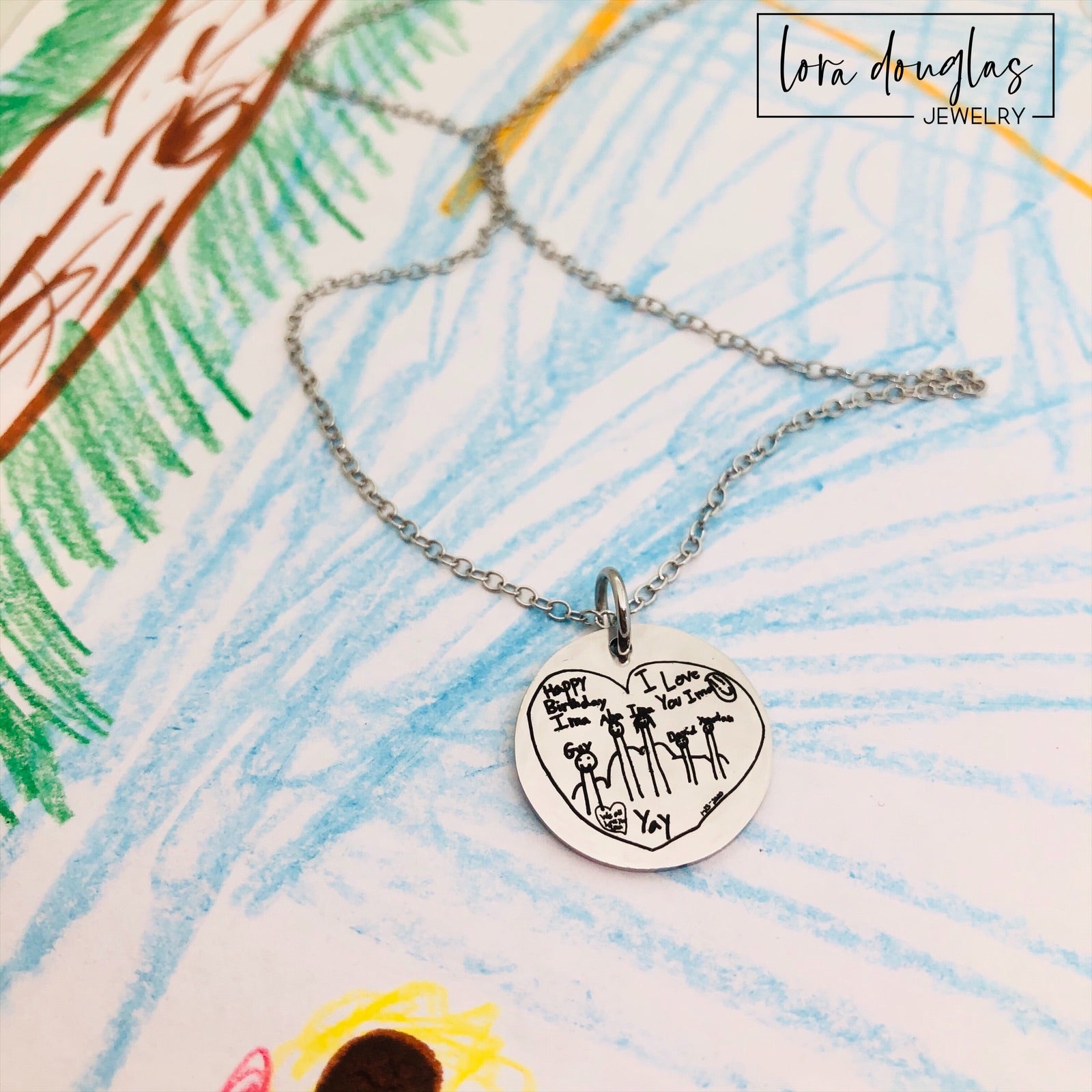 Custom artwork necklace featuring a child's handwritten drawing or doodle engraved onto a round stainless steel pendant, with silver, gold, and rose gold options for preserving a favorite piece of childhood artwork as jewelry.