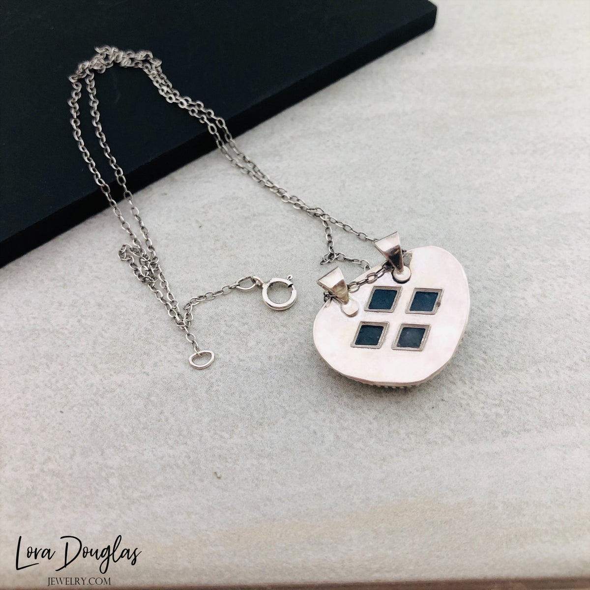 Detailed view of a natural aquamarine gemstone in a 20mm x 23mm sterling silver pendant, highlighting the soft blue stone and silver setting of this necklace with an 18 inch antique patina chain.

