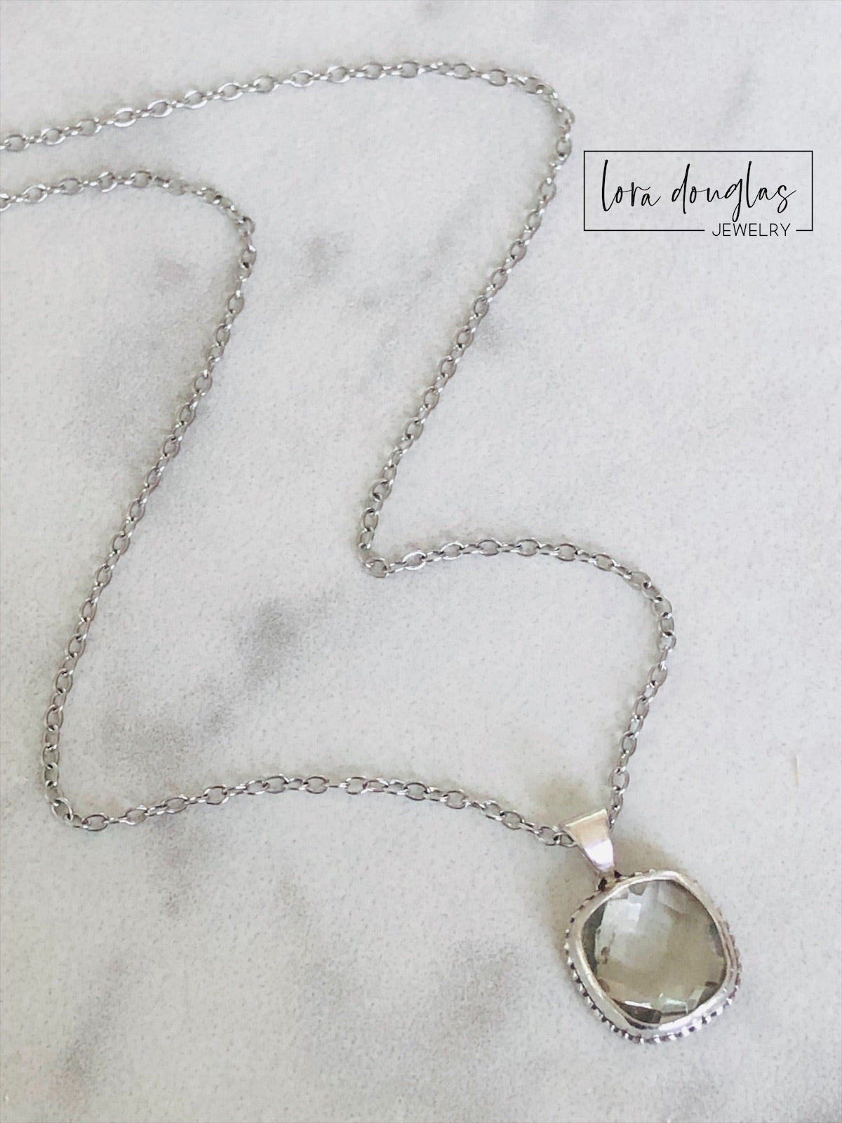 Detailed view of an 11mm faceted green amethyst gemstone set in sterling silver, showing the hand cut surface and soft green color of prasiolite in this pendant measuring 18.5mm x 12.5mm overall.
