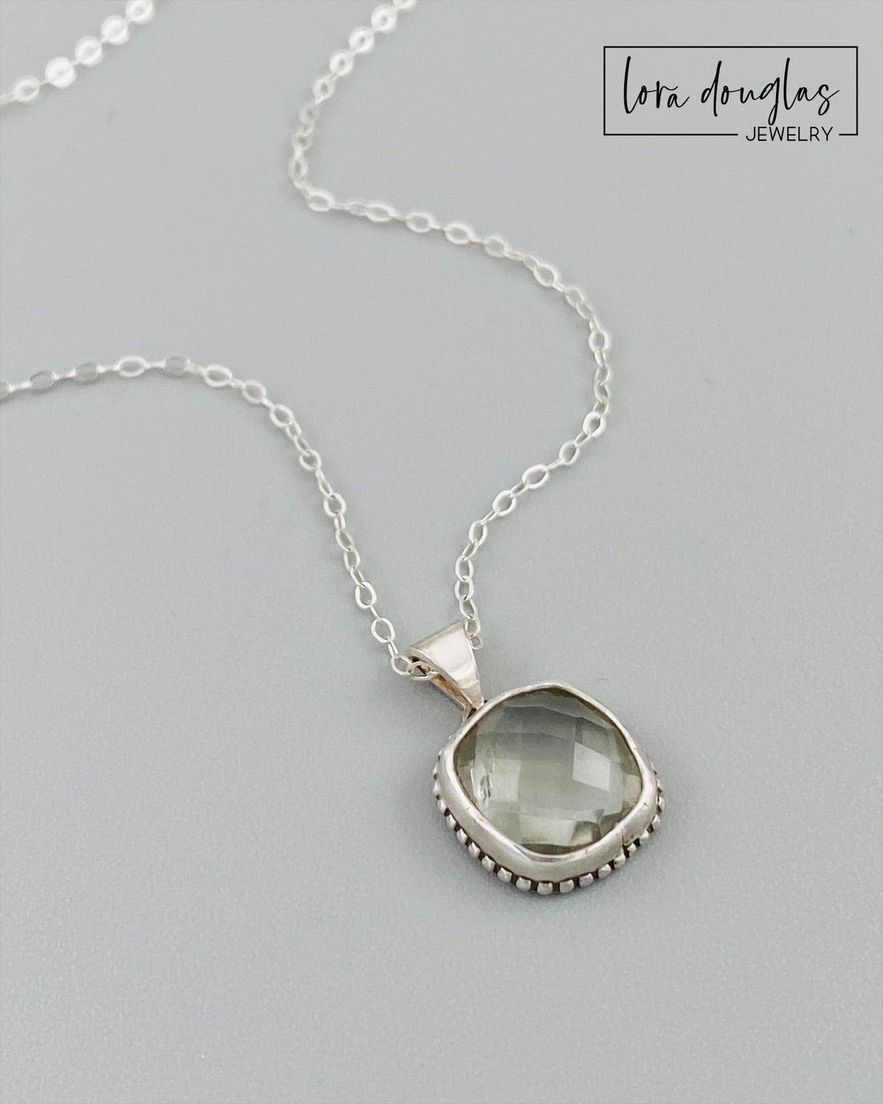 Faceted prasiolite pendant necklace featuring a soft green 11mm gemstone in a sterling silver setting, with a total pendant size of 18.5mm x 12.5mm and an 18 inch sterling silver chain.
