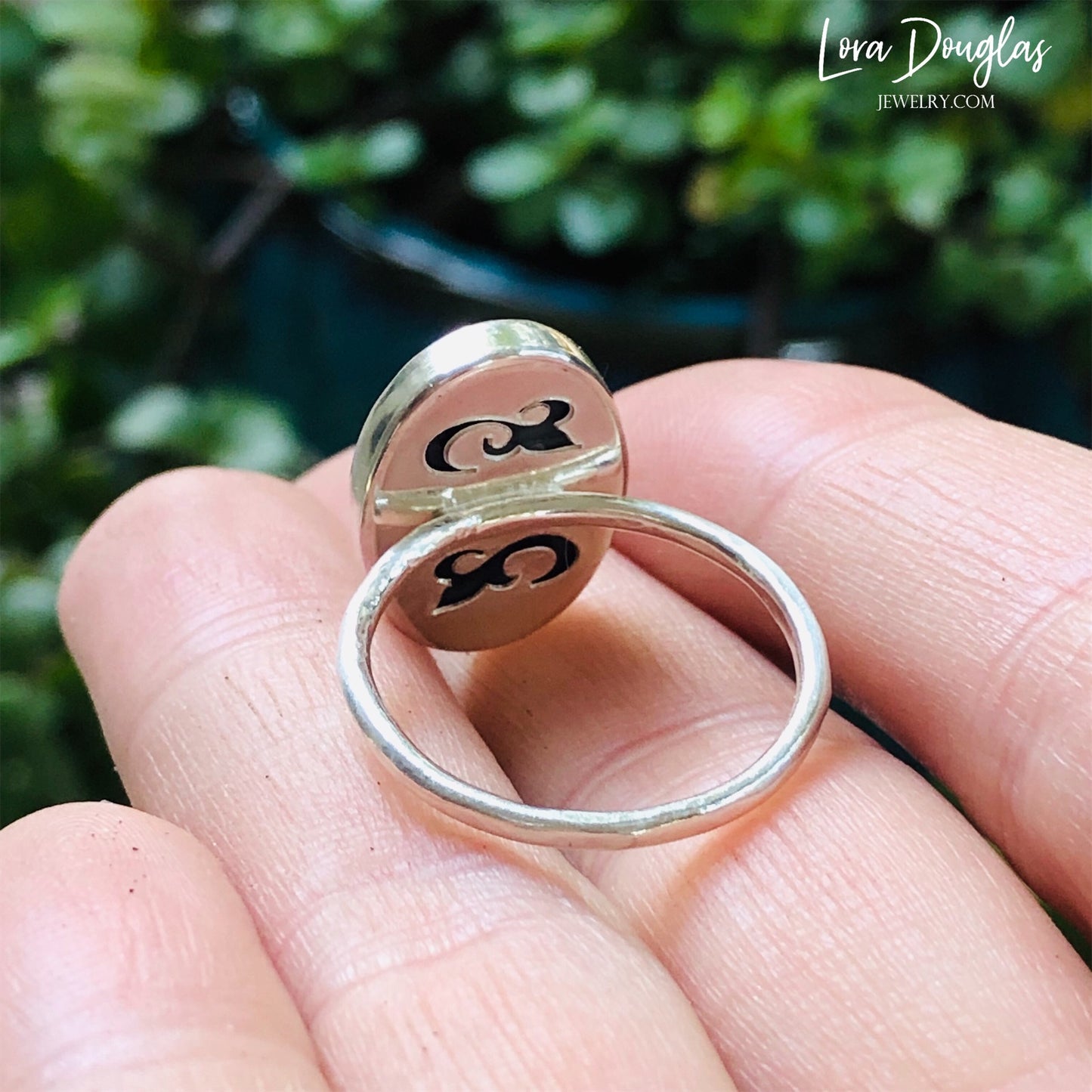 A sterling silver sodalite ring on a woman's finger, with a close-up on the ring showing the blue sodalite stone surrounded by a silver band.