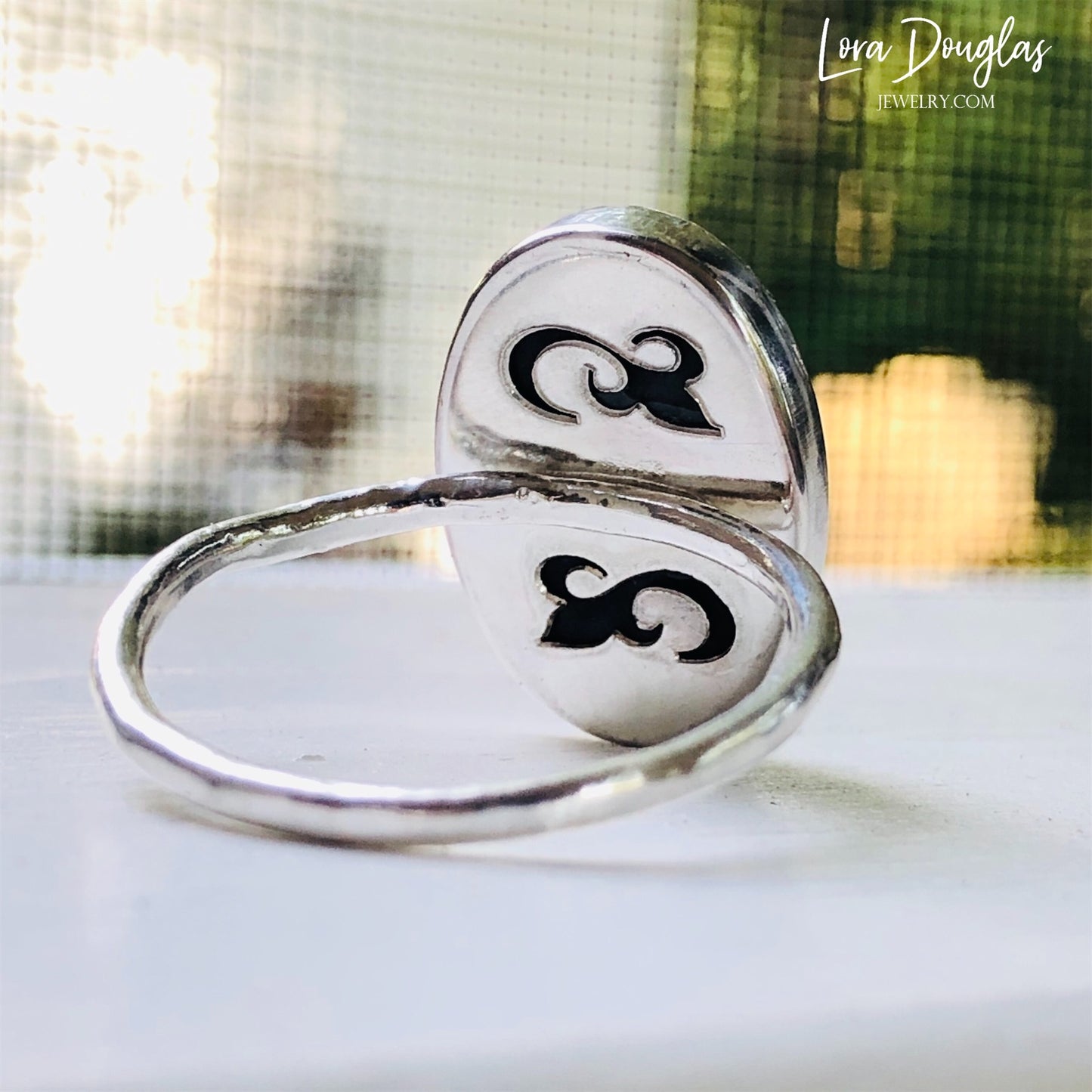 A sterling silver sodalite ring on a woman's finger, with a close-up on the ring showing the blue sodalite stone surrounded by a silver band.