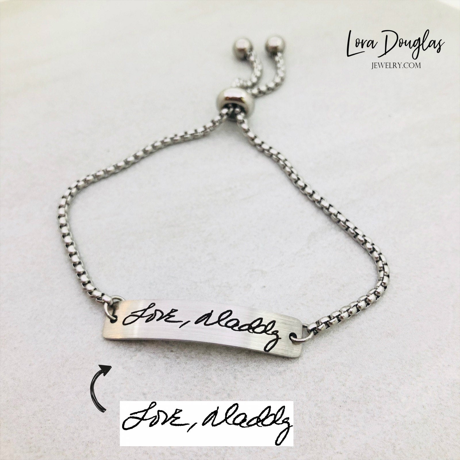 Adjustable stainless steel bracelet engraved with a handwritten message.