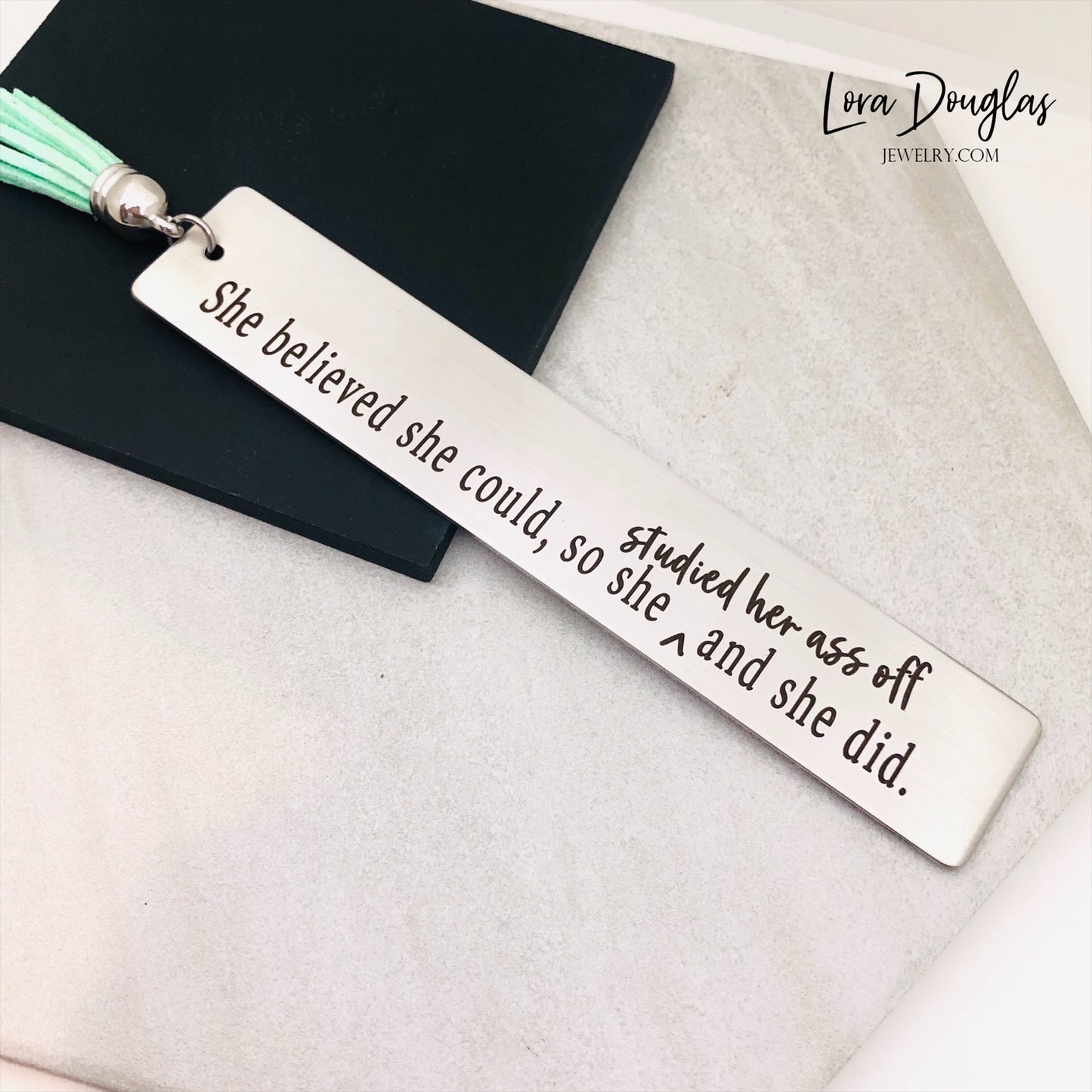 Inspirational metal bookmark engraved with "She Believed She Could So Studied Her Ass Off And She Did" with a colorful tassel. Thoughtful gift for college students, graduates, avid readers, teachers, and anyone reaching a major milestone.