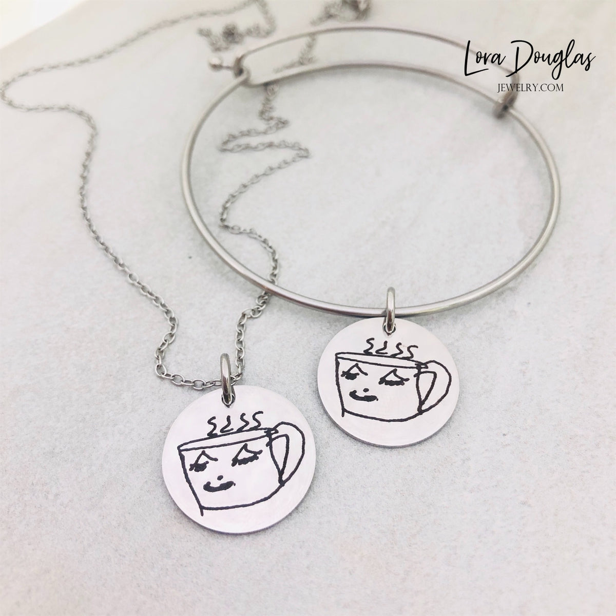 Kids drawing keepsake jewelry with a child's artwork engraved onto a round stainless steel disc, available in five pendant sizes and three metal colors for a personalized Mother's Day, Father's Day, birthday, or Christmas gift.